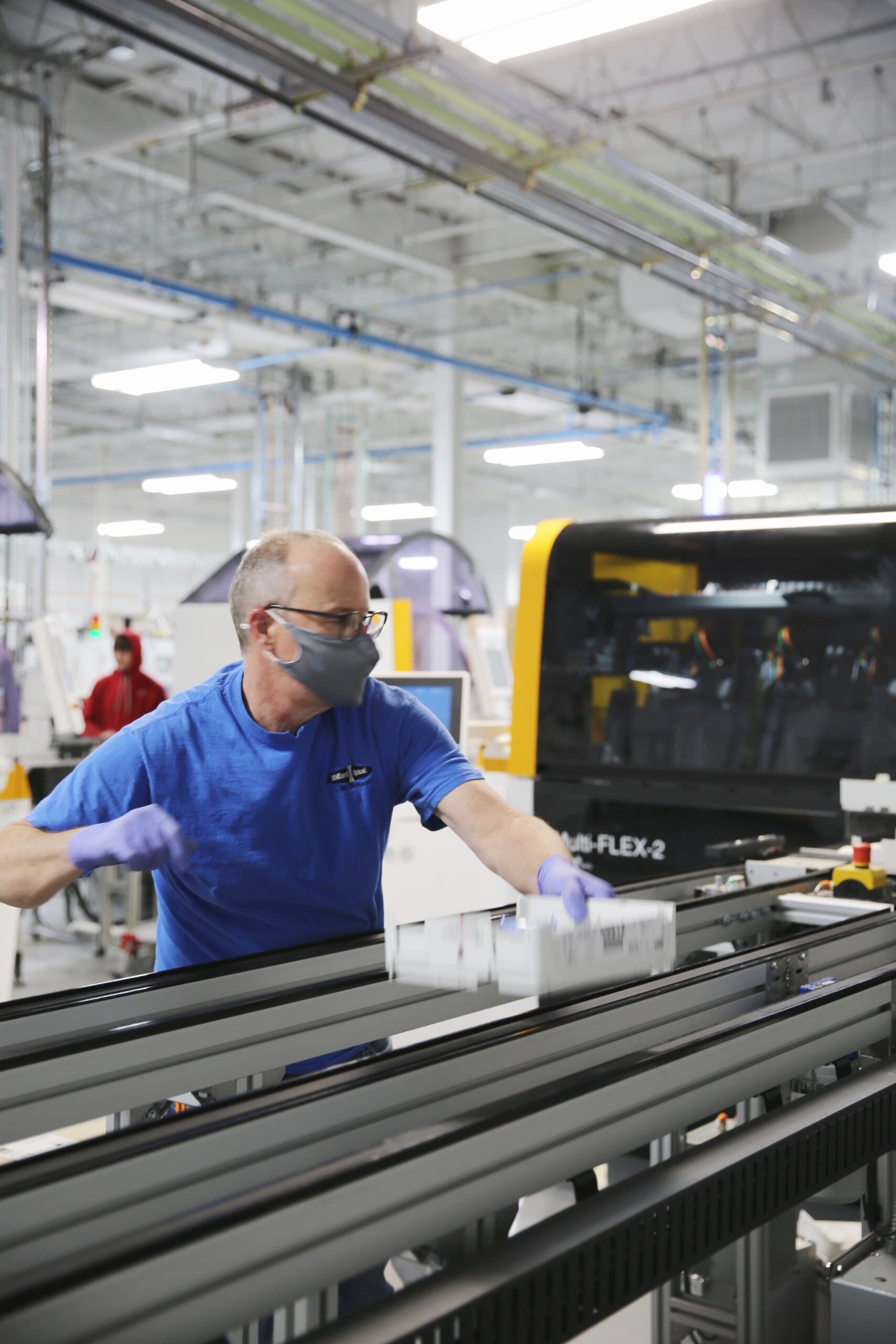 Man processing lenses down a conveyor belt